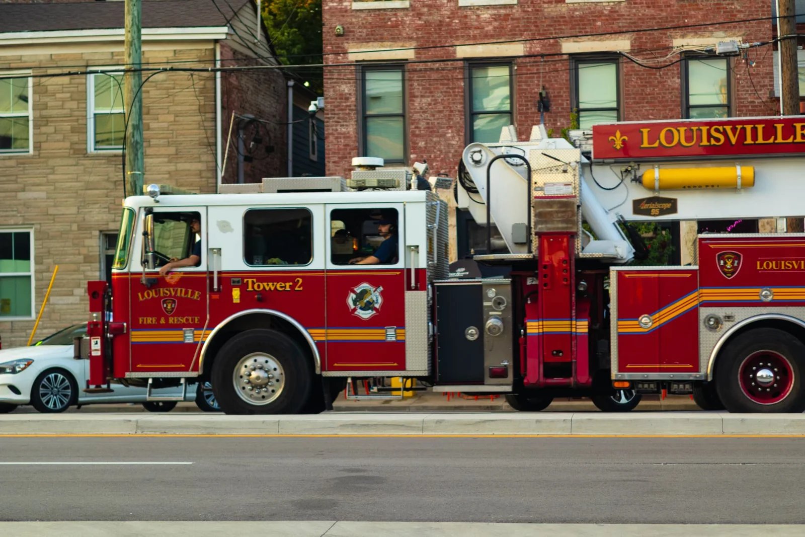 Louisville Fire & Rescue Tower 2 truck passing brick buildings