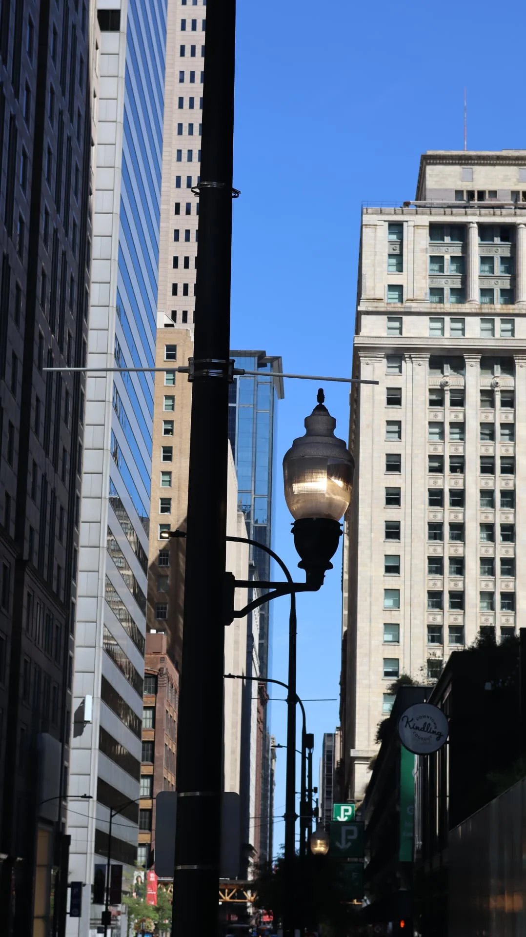 Ornate street lamp framed between Chicago towers under blue sky
