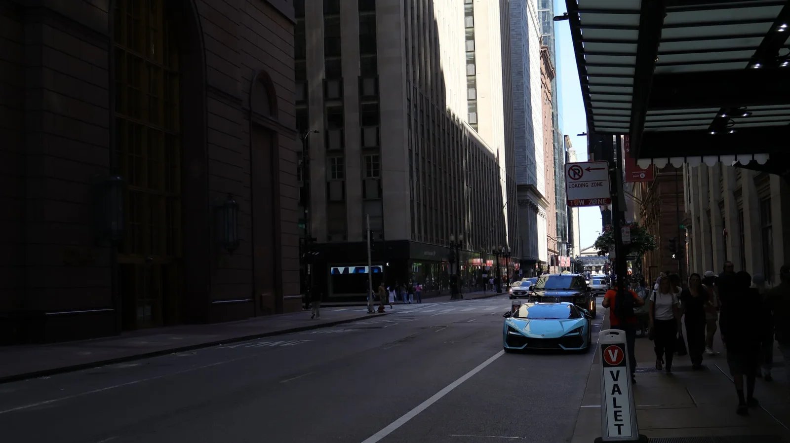Shadowed downtown street with a light blue sports car at the curb